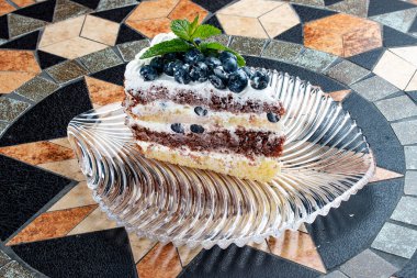 Ekşi kremalı ve yaban mersinli kek. Taş bir dekoratif masanın üzerinde.