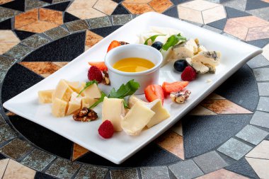Peynir tabağı çeşitli peynirler, meyveler, fındık ve bal ile servis edilir.