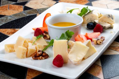 Peynir tabağı çeşitli peynirler, meyveler, fındık ve bal ile servis edilir.