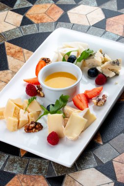 Peynir tabağı çeşitli peynirler, meyveler, fındık ve bal ile servis edilir.