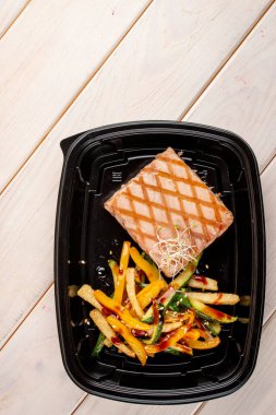 Beyaz ahşap arka planda ızgara sebzeli ton balığı bifteği. Paket servis. Diyet ve sağlıklı yiyecekler.