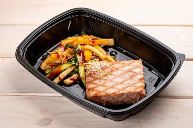 Beyaz ahşap arka planda ızgara sebzeli ton balığı bifteği. Paket servis. Diyet ve sağlıklı yiyecekler.