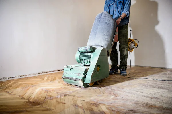 Sanding hardwood floor with the grinding machine. Repair in the apartment.