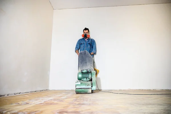 Hartholzboden mit der Schleifmaschine schleifen. Reparatur in der Wohnung. — Stockfoto