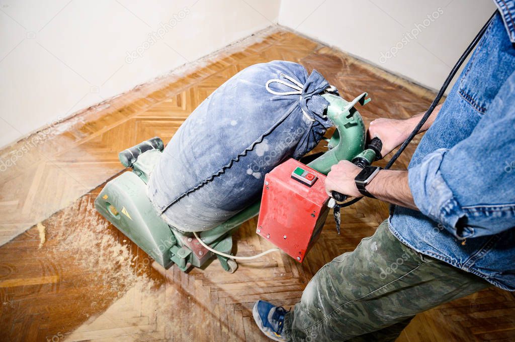 Sanding hardwood floor with the grinding machine. Repair in the apartment.
