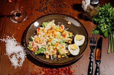 Tahta masadaki siyah tabakta Sezar salatası. Eski ahşap masada taze sezar salatası.