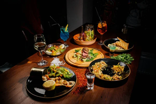 Masada bir sürü farklı lezzetli yemek var. Masada çeşitli abur cuburlar ve antipastalar var. Restoran menüleri. Restoran masası, bir sürü farklı yemek..