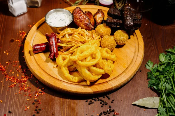 Bira ve abur cubur seçimi. Cips, balık, bira sosu. Masanın üzerinde soslu, koyu arkaplanda bir sürü farklı bira aperatifi.