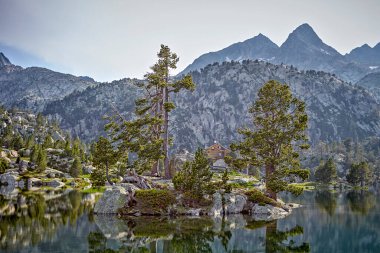 Dağ kulübesi ve kristal bir göle yansıyan ağaçlarla Idyllic dağ manzarası