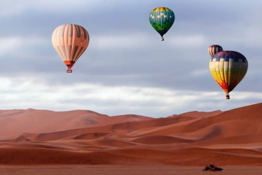 Güzel Renkli Sıcak Hava Balonları ve dramatik bulutlar Namib çölündeki kum tepeleri üzerinde