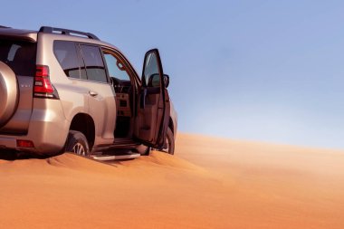 Namib çölünde kumda sıkışmış altın bir arabanın yakınında.. 