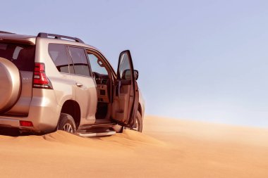 Namib çölünde kumda sıkışmış altın bir arabanın yakınında. Afrika