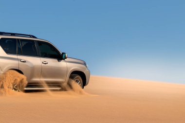 Namib çölünde kumda sıkışmış altın bir arabanın yakınında. Afrika