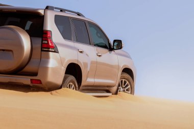 Namib çölünde kumda sıkışmış altın bir arabanın yakınında. Afrika