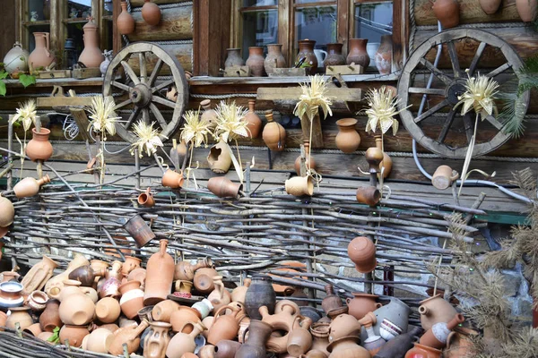 Tonkrüge und Töpfe auf dem Hintergrund eines Holzhauses mit Weidenzaun — Stockfoto