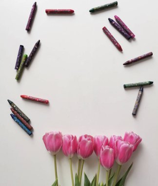 Renkli çocuk kalemleriyle pembe laleler. Beyaz arkaplanda bir bahar buketinin üst görüntüsü.