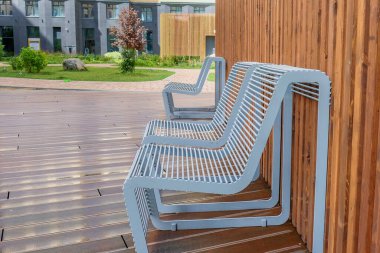 Yağmurlu bir günde bir yerleşim alanının avlusunda bir dinlenme yeri. Islak ahşap kalkanın arka planına yakın modern tasarım yağmur damlaları olan iki ıslak metal sandalye. Rahat kentsel mobilyalar..