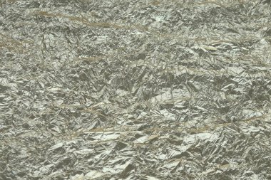 Özet desenli, buruşuk, alüminyum folyo arka plan. Arka plan için buruşuk folyo kağıdı dokusu. Arkaplan için biraz gümüş ve altın içeren buruşuk folyonun yüzeyi..