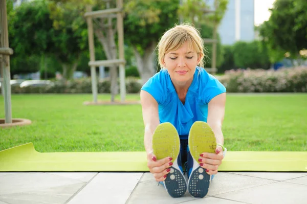Young athletic woman exercising outdoors: cool down and stretch for flexibility — Stock Photo, Image
