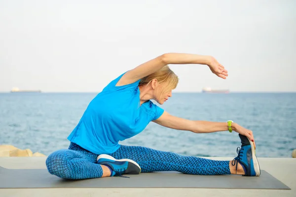 Young athletic woman exercising outdoors: cool down and stretch for flexibility — Stock Photo, Image