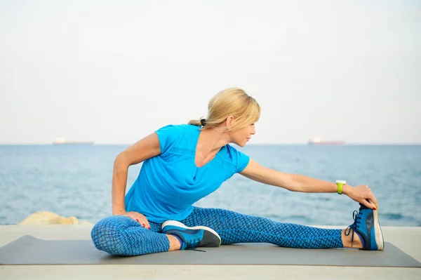 Young athletic woman exercising outdoors: cool down and stretch for flexibility — Stock Photo, Image