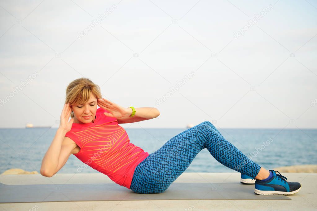 Young athletic woman exercising outdoors: crunch for abdominal strength