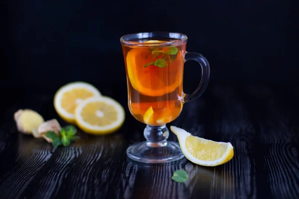 Glass transparent cup of tea with lemon, ginger and mint on the black background — Stock Photo, Image