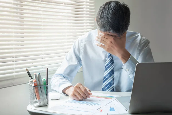 Young businessman face palming while reading business reports in the office with laptop computer. Business and finance, work in trouble concept.