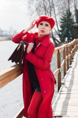 Genç bir kadın bulutlu bir havada köprüde duruyor.