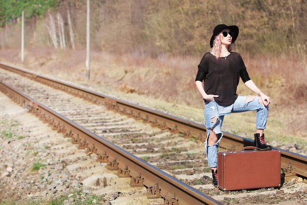 Young traveling woman with a suitcase on the railway