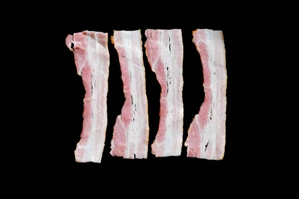 Fatias de bacon frito fresco em uma panela em um fundo preto — Fotografia de Stock