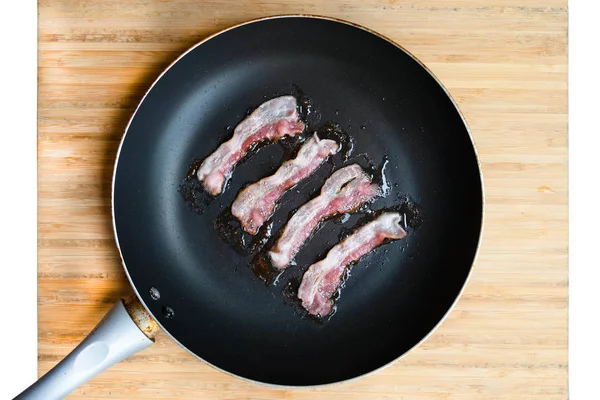 Fette di pancetta fritta fresca in padella su fondo bianco — Foto Stock