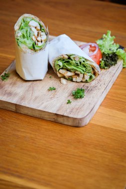 Wrap chicken or tasty kebab with vegetables on wooden