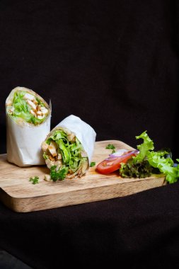 Wrap chicken or tasty kebab with vegetables on wooden