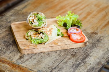 Wrap chicken or tasty kebab with vegetables on wooden