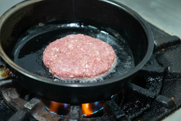 Beef burgers cooking on frying pan in kitchen