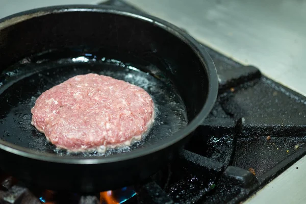 Beef burgers cooking on frying pan in kitchen