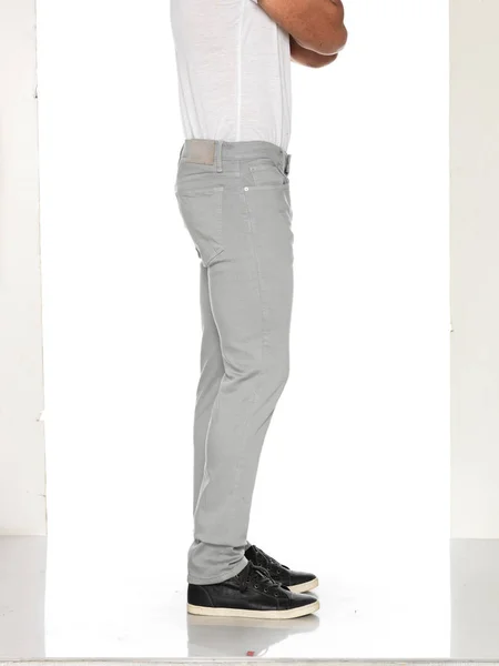 Trendy slim fit light grey men denim paired along black sneakers with white background — ストック写真