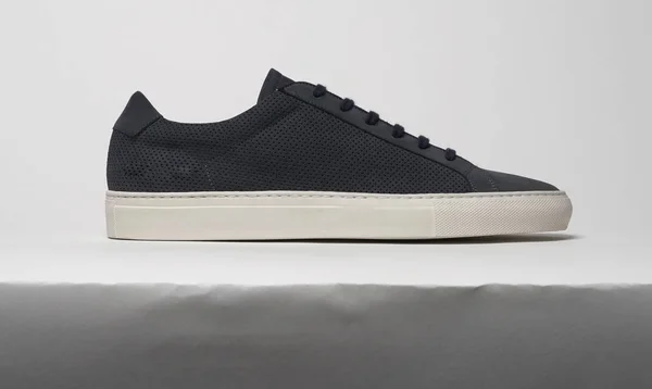 Beyaz zemin ve beyaz arka planı olan lacivert spor ayakkabılar.