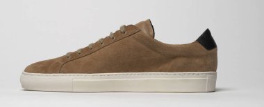 Beyaz zemin ve beyaz arka planı olan kahverengi spor ayakkabılar.