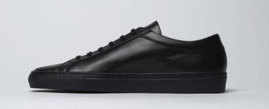 Siyah ve beyaz arka planlı siyah spor ayakkabılar.