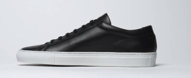 Siyah ve beyaz arka planlı siyah spor ayakkabılar.