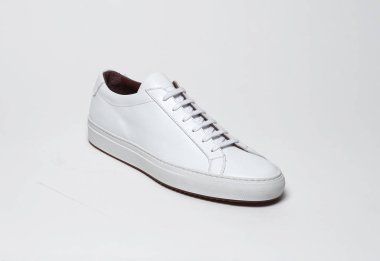 Beyaz zemin ve beyaz arka planda beyaz spor ayakkabılar, beyaz arka planda sade beyaz spor ayakkabılar.