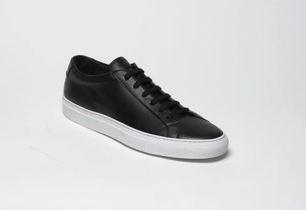Siyah ve beyaz arka planlı siyah spor ayakkabılar. — Stok fotoğraf