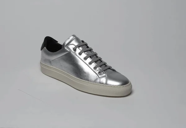 Zapatillas de deporte de color plata brillante con base blanca y fondo blanco Imagen De Stock