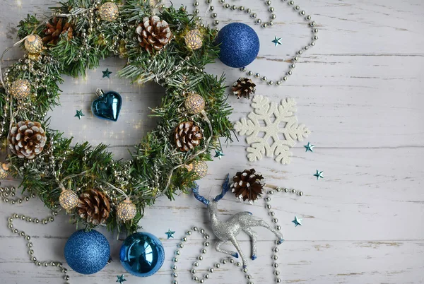 Christmas composition of fir wreath, blue balls, cones, snowflakes on a light wooden background — Stock Photo, Image