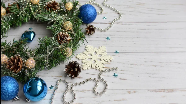 나무로 만든 가벼운 탁자 위에 놓인 파란색 크리스마스 장난감 과 크리스마스 화환의 근접 사진 — 스톡 사진