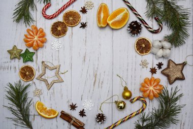 Portakal dilimleri, mandallar, ladin dalları, Noel oyuncakları, koniler, tarçın çubukları, şekerler, hafif ahşap zeminde kar taneleri Noel kompozisyonu