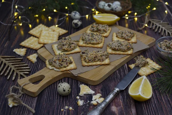 Appetizing crackers with paste on a cutting board, lemon slices and a knife on table. — Stock Photo, Image