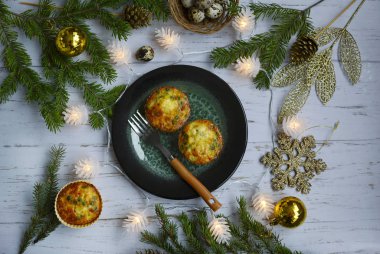 Top view on a light wooden table with delicious vegetable muffins, garlands and New Year's decor clipart